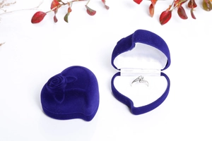 Detail of dark blue heart-shaped velvet ring box with rose embossed pattern