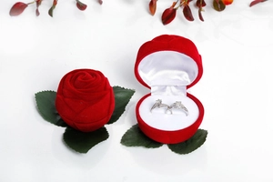 Detail view of red rose shaped velvet jewelry box for rings with green fabric leaves
