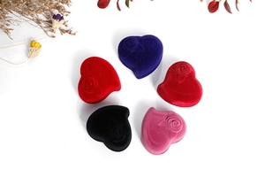 Macro detail of heart-shaped velvet ring boxes with embossed rose patterns in multiple colors