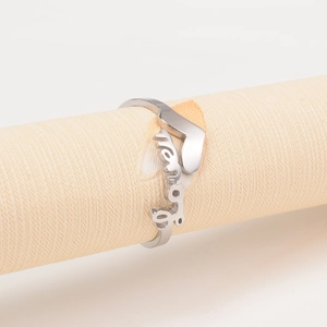 Gros plan sur une bague argentée avec cœur évidé et texte Love sur un support papier