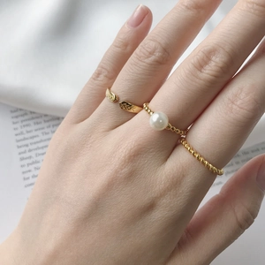 Close-up of three gold rings with pearls and black zircon worn on fingers