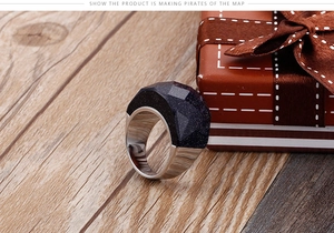 Vue détaillée d'une bague géométrique en grès bleu avec anneau argenté dans un coffret