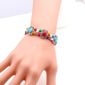 Ethnic tibetan silver bracelet with colorful beads and floral metal charms shown on hand