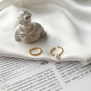 Detail of golden S925 silver rings with pearls on white silk and artistic background