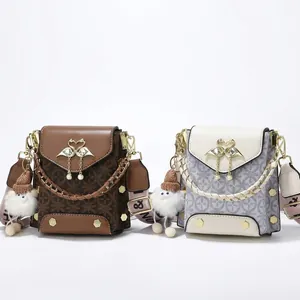 Detail of vintage crossbody bag with swan buckle, pearl tassel and wide woven strap
