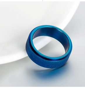 Polished blue matte stainless steel spinning ring for men shown on a white ceramic plate
