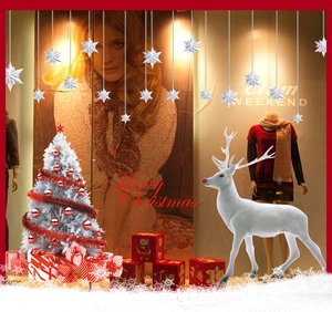 Detail von weißem Rentier, geschmücktem Weihnachtsbaum und Geschenkboxen für Schaufenster