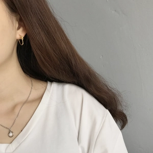 Detail of minimalist S925 sterling silver knotted hoop earring on a female model