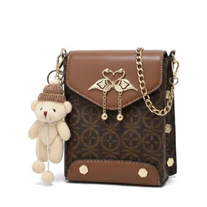 Detail of vintage brown shoulder bag with golden swan clasp and plush charm accessory