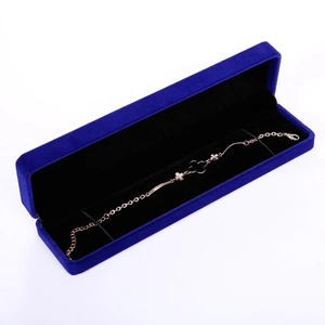 Detail of royal blue velvet jewelry box with elegant rose gold clover bracelet