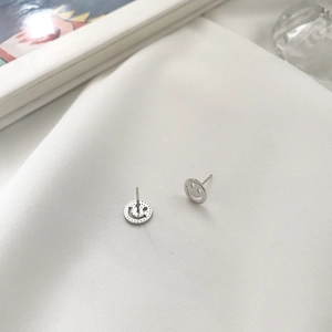 Detailed view of S925 sterling silver smiley face stud earrings on white silk fabric