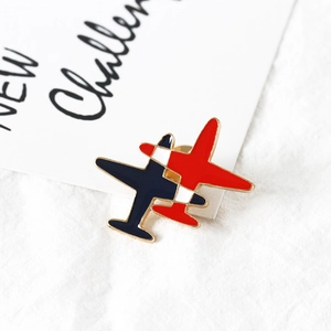 Détail d'une broche avion en émail bleu et rouge avec des contours en alliage doré