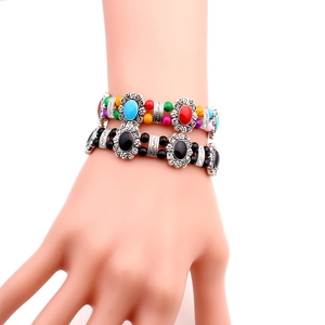 Detailed close-up of ethnic style beaded bracelets with vintage silver flower charms
