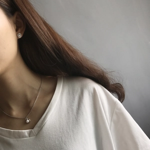 Close-up of S925 sterling silver smiley face earring and delicate pearl pendant necklace