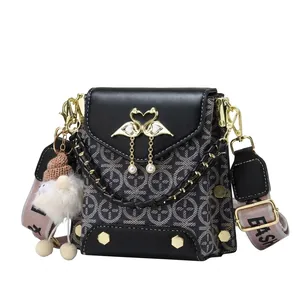 Detail of vintage patterned crossbody bag with swan metal clasp and pearl pendant accent