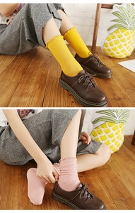 Detail of yellow and pink ribbed knit socks with cute ruffled edges worn with brown shoes