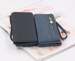 Detail view of long wallets in black and blue-grey with wrist straps and gold zippers