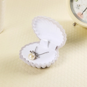 Détail d'un écrin à bijoux en forme de coquillage en velours avec un collier de perles
