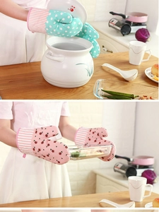 Detail of floral and polka dot oven mitts holding a hot ceramic lid and glass tray