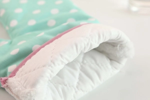 Detailed macro view of quilted cotton lining and pink trim on polka dot oven mitt