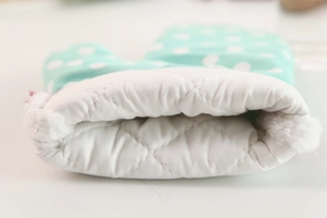 Close-up of quilted plaid oven mitt with soft white lining and blue polka dot pattern