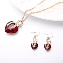 Detailed view of heart-shaped red gemstone jewelry set with gold alloy accents and crystals