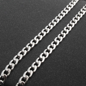 Macro shot of silver Cuban link chains showing interlocking metal details on black background