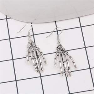 Detailed close-up of vintage silver skeleton hand drop earrings on a checkered background