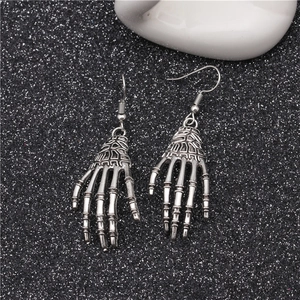 Macro detail of gothic skeleton palm hand earrings in vintage silver finish on dark background