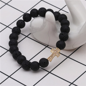 Close-up of lava stone beaded bracelet with a gold-plated zircon cross charm on hand model