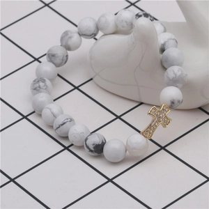 Detail of white turquoise beaded bracelet featuring a gold-plated zircon cross pendant