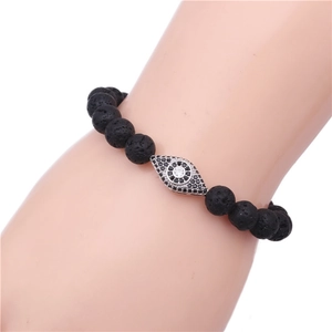 Macro detail of black lava stone beaded bracelet with zircon evil eye charm on a wrist