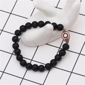 Macro shot of evil eye charm with pavé crystals on black matte beaded elastic bracelet