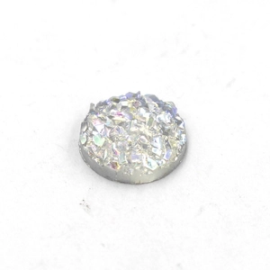 Macro shot of 8mm round iridescent resin cabochon with sparkling crystal cluster surface