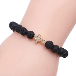 Macro view of matte black beads bracelet with gold cross pendant encrusted with cubic zirconia
