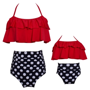 Close-up of matching mother-daughter bikini sets with red ruffles and polka dot bottoms