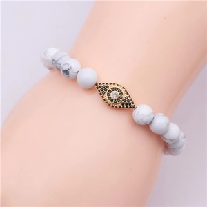 Detail of beaded bracelet with white turquoise beads and gold evil eye zircon charm