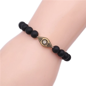 Close-up of black matte beads and gold plated evil eye charm with micro-pave stones