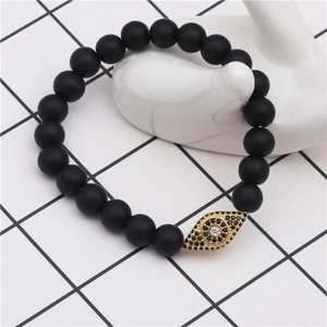 Detail of beaded bracelet with matte black stones and gold-plated cubic zirconia evil eye