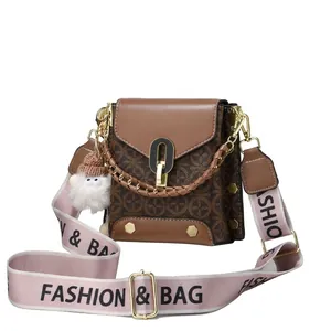 Detailed close-up of golden oval lock and rivet hardware on brown crossbody bag