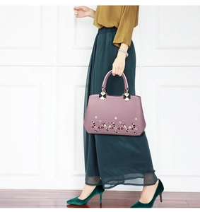 Detailed view of purple leather handbag featuring exquisite floral embroidery and dual handles