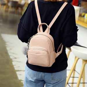Detail of pink faux leather mini backpack with furry pompom and gold zipper hardware