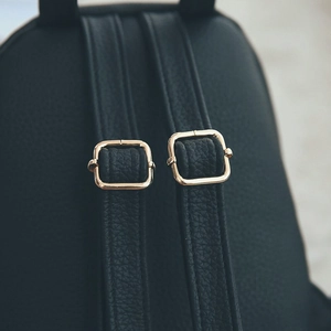 Detailed close-up of black leather backpack shoulder straps with gold metal buckles