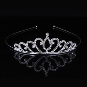 Elegant silver rhinestone crown with heart design reflecting on a glossy black surface