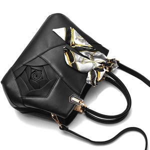 Elegant black leather handbag with rose embossed design and floral silk scarf detail
