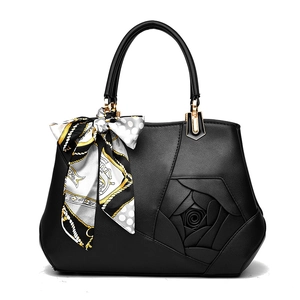Elegant black leather handbag with rose stitching and decorative scarf on white background
