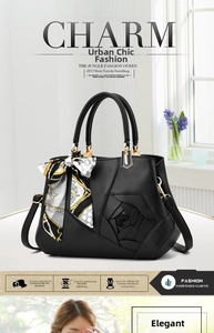 Detail showing elegant 3D rose design and silk scarf charm on black PU leather handbag