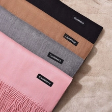 Detail of four cashmere scarves in pink grey camel and black with fringe and tags