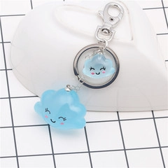 Detail of blue smiling cloud charms keychain made of matte resin in a white ceramic dish