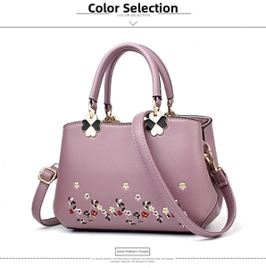 Detailed view of lavender leather handbag with floral embroidery and clover decorations